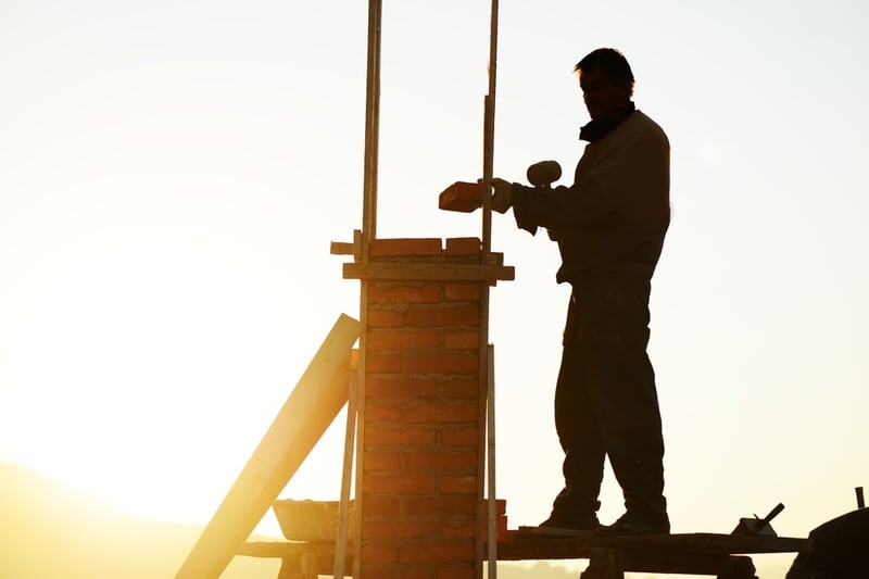 Silhouette of worker building a chimney on new house-1